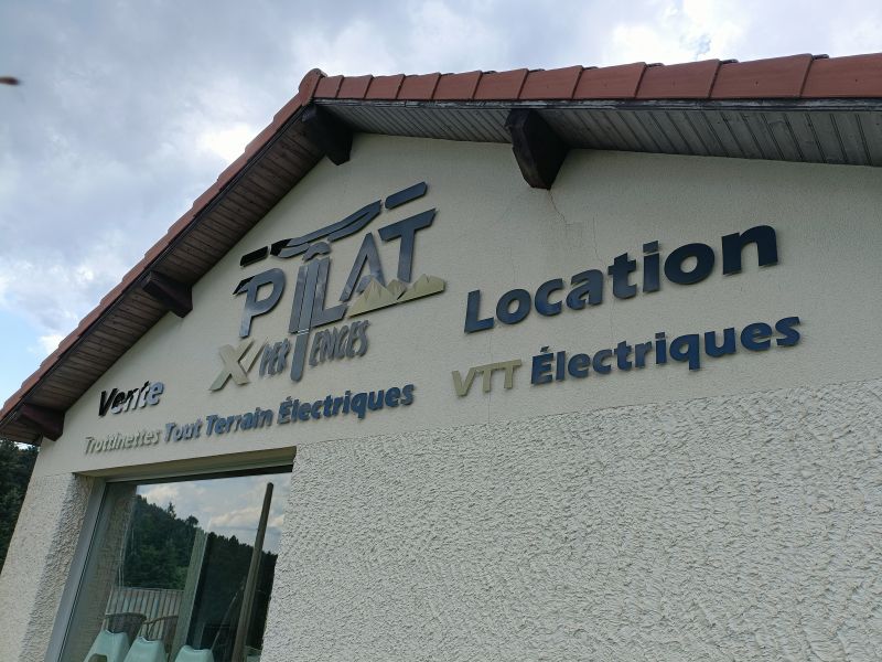 Réalisation d’enseigne avec logo et lettres découpées sur entretoises, façade d’un bâtiment dans le Massif du Pilat